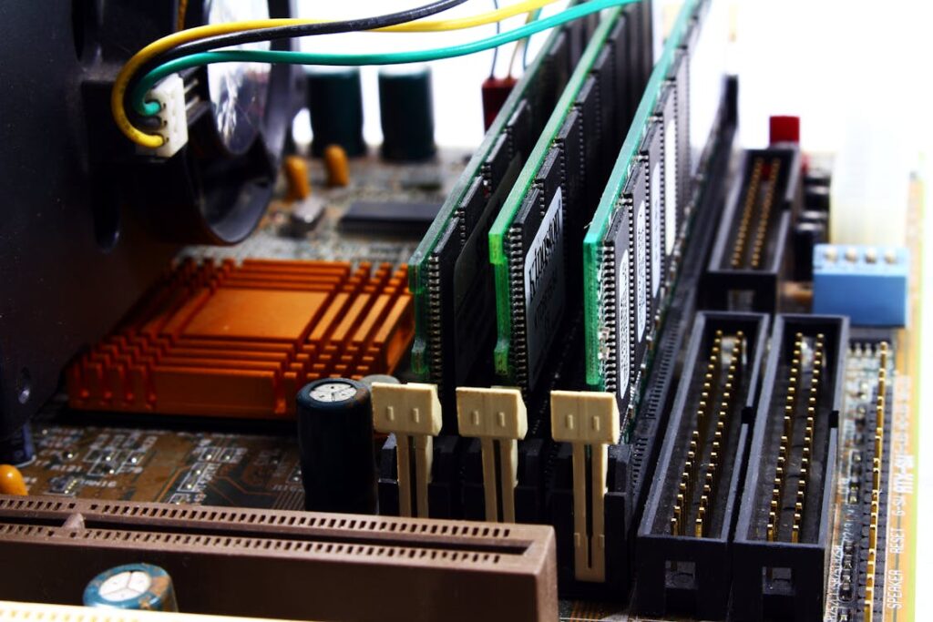 Close-up view of a computer motherboard showing RAM modules, orange CPU heat sink, and various connectors.